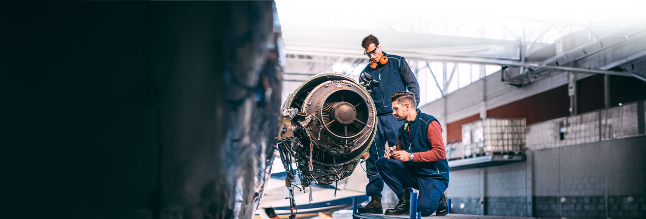 Zwei Flugger&auml;tmechaniker kontrollieren ein Flugzeugtriebwerk und f&uuml;hren gemeinsam Inspektions- und Wartungsarbeiten durch.