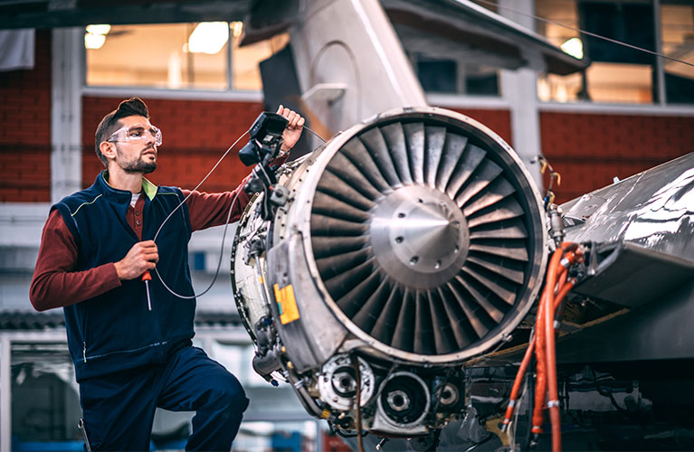 Ein Flugger&auml;tmechaniker &uuml;berpr&uuml;ft ein Flugzeugtriebwerk mit modernem Messequipment und erweitert seine technischen Kenntnisse durch kontinuierliche Weiterbildung.