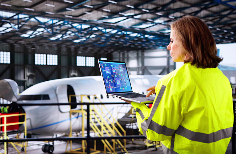 Eine Luftfahrtingenieurin analysiert technische Systeme am Laptop, plant Wartungs- und Optimierungsma&szlig;nahmen und erweitert ihr Fachwissen durch kontinuierliche Weiterbildung in der Luftfahrttechnik.