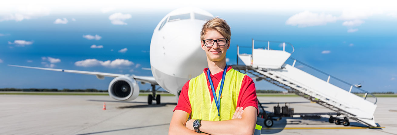 Mitarbeiter mit Warnweste und Headset steht vor Flugzeug auf dem Rollfeld